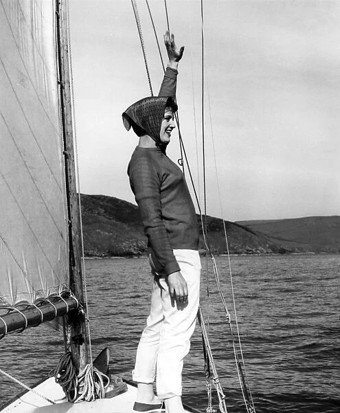 Girl in headscarf at the front of a sailing boat waving
