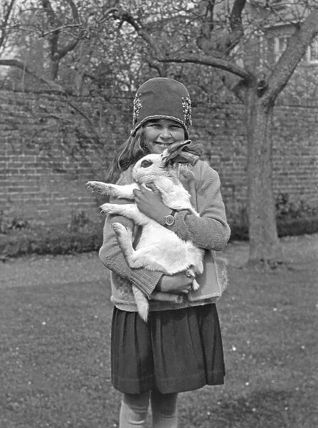 Girl holding rabbit in a garden