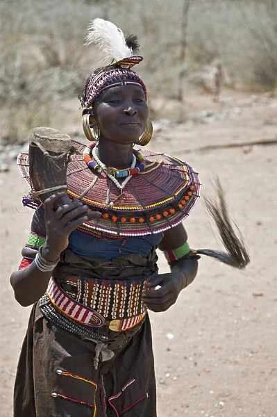 An old Pokot woman dancing during an Atelo ceremony. The cow horn container usually contains animal fat