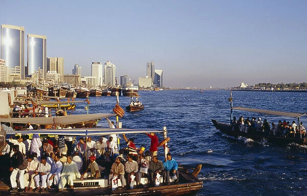 UAE, Dubai, Dubai Creek Abra water taxis with passengers on Creek with city skyline