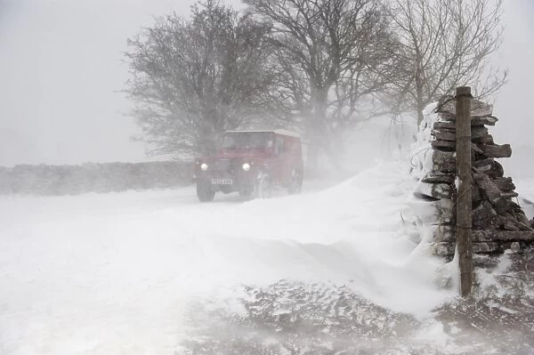 Land Rover travelling along rural road during severe snowstorm, A685, near Ravenstonedale, Cumbria, England, March