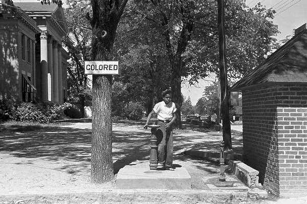 SEGREGATED FOUNTAIN, 1938. A boy drinking from a segregated water fountain on the