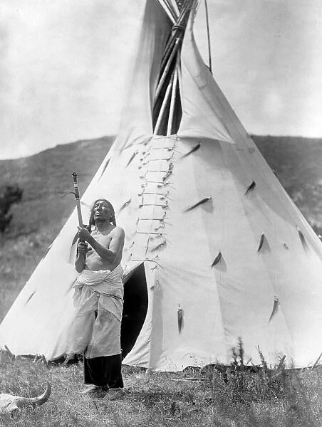 SIOUX AND TIPI, c1907. Slow Bull, a Sioux Native American medicine man, standing