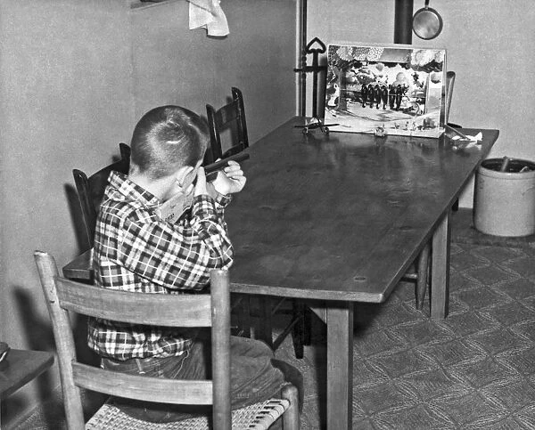 A boy shoots at a birds on a wire game with a cork gun on the family table