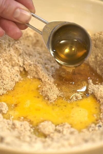 Hand pouring egg and syrup to biscuit mixture