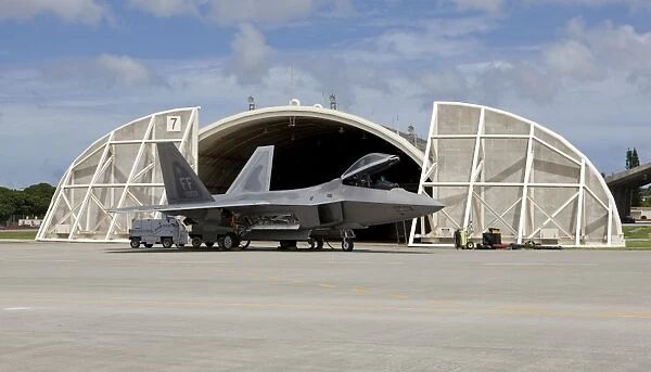 An F-22 Raptor parked in front of a hardened aircraft shelter at Kadena Air Base