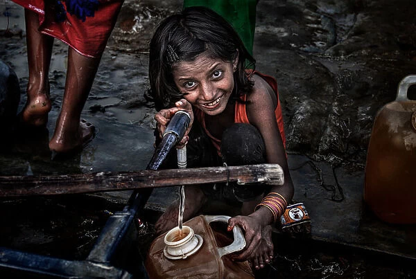 Rohingya refugee girl filling a container of water - Bangladesh