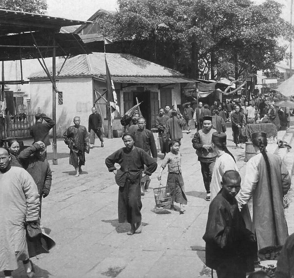 Historic image in black and white of Chinese people on a busy street in a Chinese city circa 1900, contrasting middle class and lower class; China