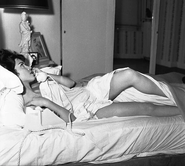 Actress Jackie Lane lying naked on the bed talking on the phone March 1959