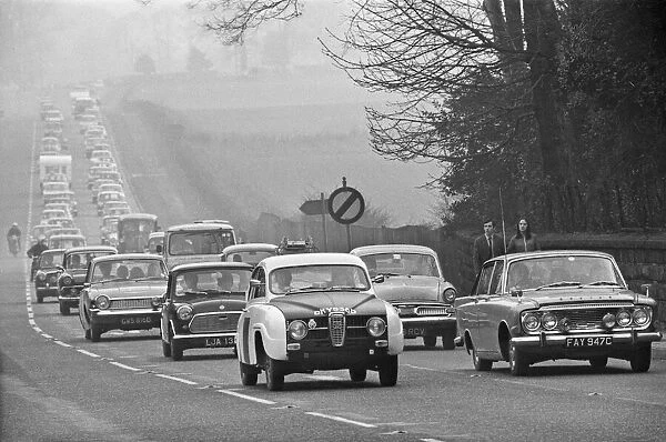 Pedestrians look over at the traffic built up along the A556 towards Manchester