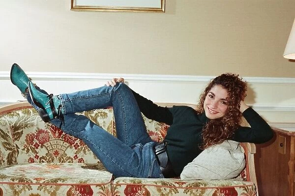 Pop singer Gloria Estefan poses lying down on a sofa in her hotel room on a visit to