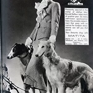 Advertisement for Matita Ltd, clothing, with Mrs Balfour and two lurchers, fashion studio portrait. With description, Pleasantly assured in the matter of clothes, Mrs Ronald Balfour takes stock for another year