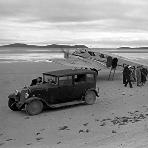 People on sandy beach with cars and light aircraft, Scotland