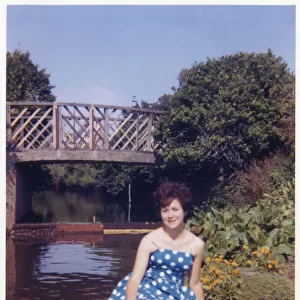 Pretty Young lady in a blue and white dress in a public park