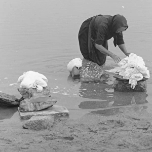 Woman sorting out washing in a river