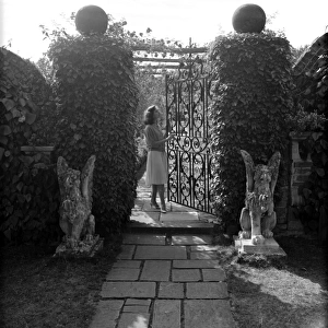 Wrought iron gate in a garden with female model