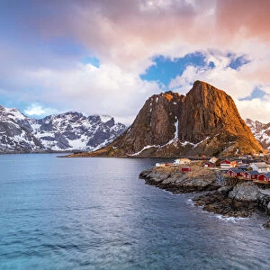 Clouds at sunrise over traditional Rorbu cottages on cliffs by the cold arctic sea, Hamnoy, Reine, Lofoten Islands, Norway, Europe