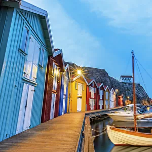 Colorful fishing huts with wooden boat moored at the jetty at dusk, Smogen, Bohuslan, Vastra Gotaland, West Sweden, Sweden, Scandinavia, Europe