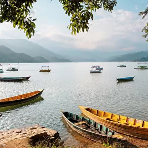 Colourful boats in front of Himalayan peaks on Lake Pokhara in Pokhara, Nepal, Asia