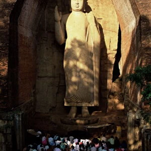 Pilgrims seated in front of the 39 ft high standing Buddha