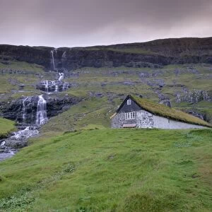 Traditional turf roofed farm building and waterfall, Saksun, Streymoy Island