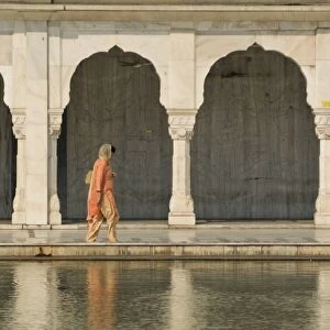 Traditionally dressed woman walking along one of the pools at the Bangla Sahib Sikh Temple in Delhi