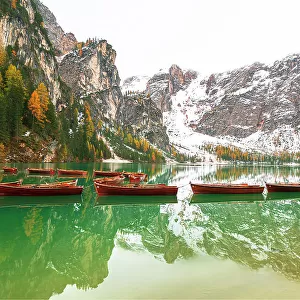 Wooden boats floating on calm waters of Braies lake, autumn view, Braies, South Tyrol, Bozen province, Italy, Europe