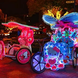 Illuminated decorated kitsch cycle trishaw rickshaw with soft toys at night in Malacca, Malaysia