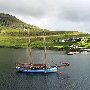 The Faroese-built wooden sailship Norðlysið (The Nordic Lights) sailing in fron of the village of Syðrugota. Island of Eysturoy. Faroe Islands