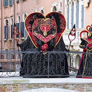 Heart-shaped costumes posing on a bridge at the Venice Carnival, Venice, Italy