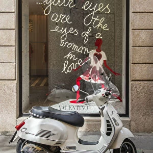 Italian Vespa scooter parked in Via Montenapoleone fashion street with Valentino shop