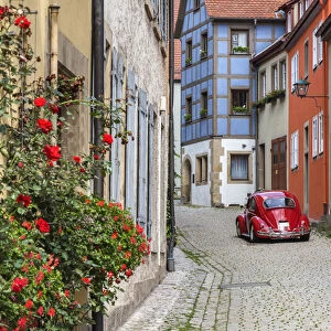 Picturesque cobblestone street with original Volkswagen Beetle car, Rothenburg ob