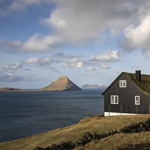 A traditional Faroese house in Velbastaður. The island of Koltur in the background. Faroe Islands