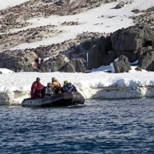 Tourists in Zodiac inflatable boat, leaving Adelie Penguin (Pygoscelis adeliae) nesting colony, Half Moon Island