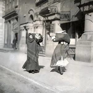 HINE: HOME INDUSTRY, 1912. Two women carrying loads of garments for piecework at home