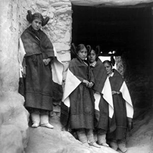 HOPI MAIDENS, 1906. A group of young Hopi women standing outside an entrance of a pueblo building in the village of Walpi, Arizona. Photographed by Edward S. Curtis, 1906