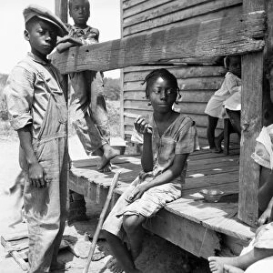 MIGRANT CHILDREN, 1936. African American children sitting on porch of a migrant