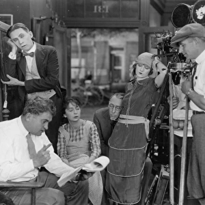 SILENT FILM SET, 1920s. Actress Viola Dana (standing) sleeps as director Edward Cline explains the script of Along Came Ruth, a Metro picture