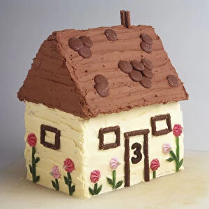 Cake in the shape of a cottage decorated with buttercream icing