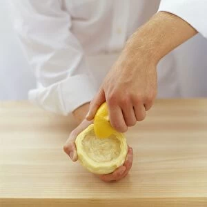 Chef squeezing lemon juice into globe artichoke