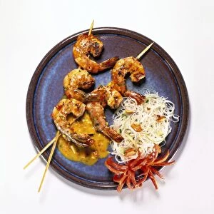 Grilled Thai-style prawns with curry sauce, noodle salad and red chilli garnish, on a plate