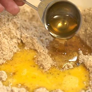 Hand pouring egg and syrup to biscuit mixture
