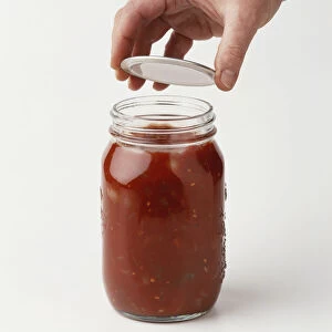 Jar of tomato relish being sealed with lid