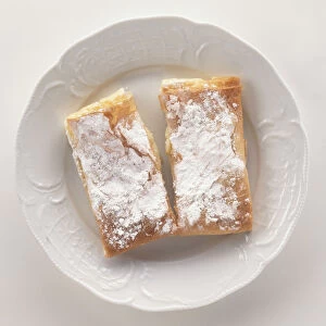 Overhead view of Bougatsa, a Greek pastry of semolina custard dusted with cinnamon and sugar, served on white plate