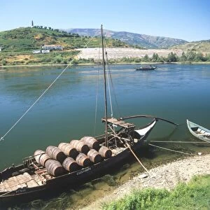 Portugal, Peso da Regua, boat loaded with barrels of port, moored on banks of river