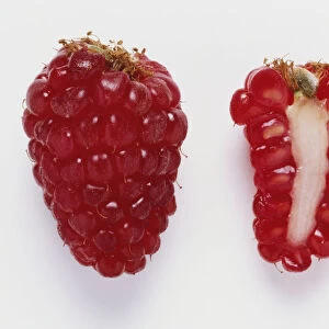 A whole raspberry beside a cross section of a raspberry
