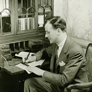 Man writing letter at bureau, (B&W)