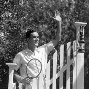 Smiling man in tennis whites, waving