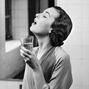 Young woman in bathroom gargling water, (B&W)
