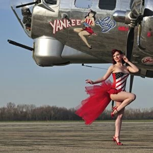Beautiful 1940s style pin-up girl standing in front of a B-17 bomber